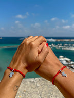 Filo Rosso-Armbänder mit Puzzle-Charm aus S925-Silber, Hände auf dem blauen Meer verbunden. Symbol der Einheit und Affinität.