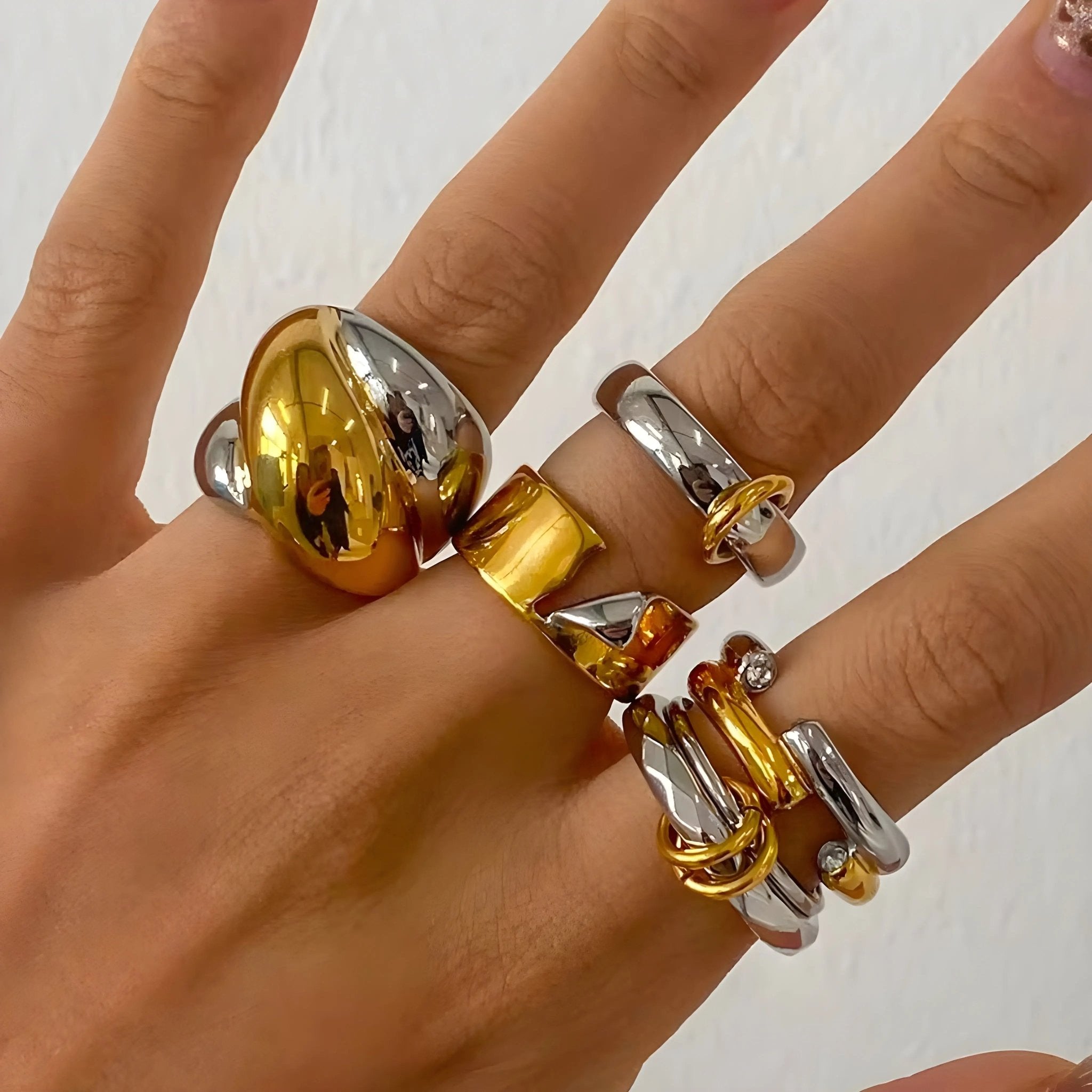 Mano con cinque anelli Charlotte BEHI MILANO bicolore oro 18k e argento. Gioielli raffinati in acciaio inossidabile.