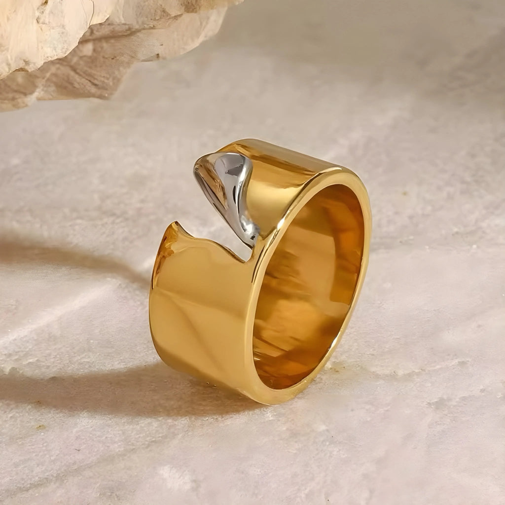 Anello Charlotte BEHI MILANO in acciaio placcato oro 18k PVD, con elemento lucido argento, su sfondo chiaro.