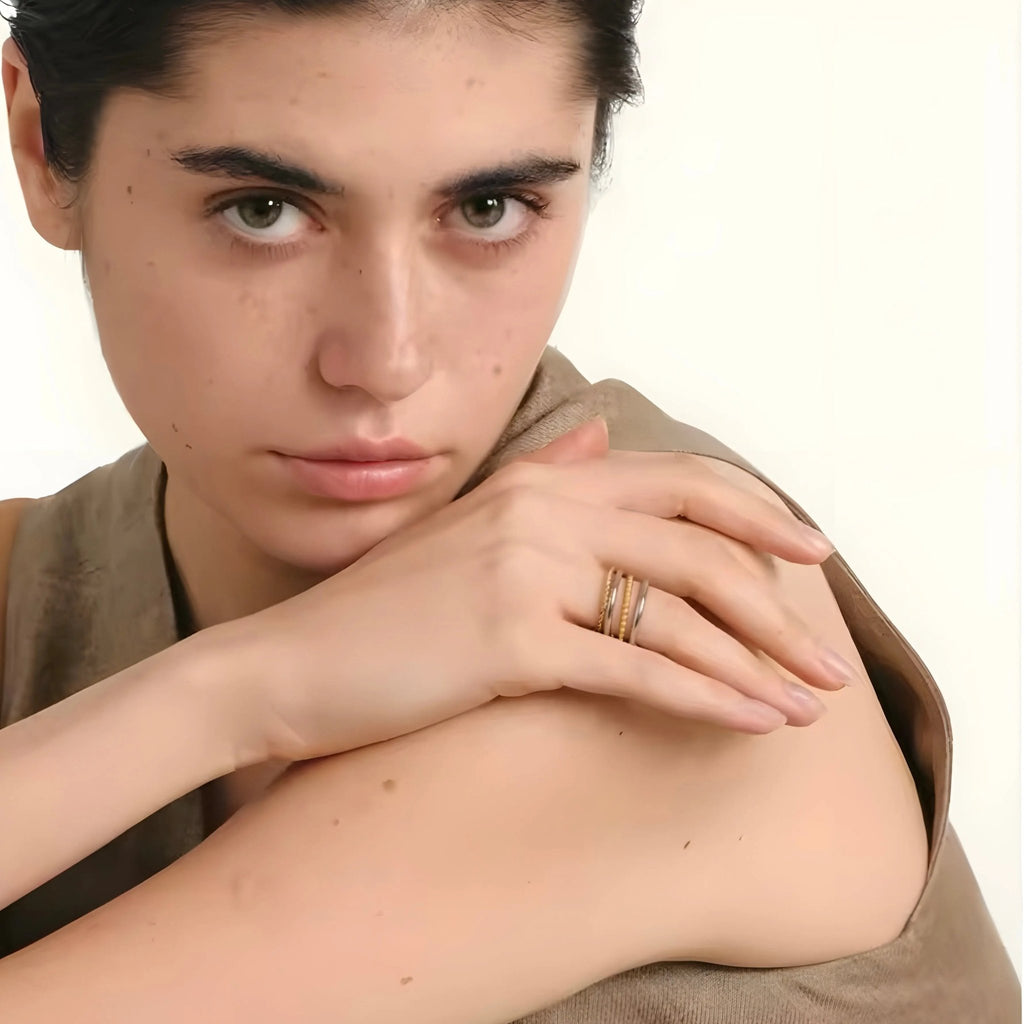 Das Model trägt einen zweifarbigen Onda-Ring aus 18 Karat Gold und Stahl von BEHI MILANO mit modernem und elegantem Design am Finger. Raffiniertes Juwel.