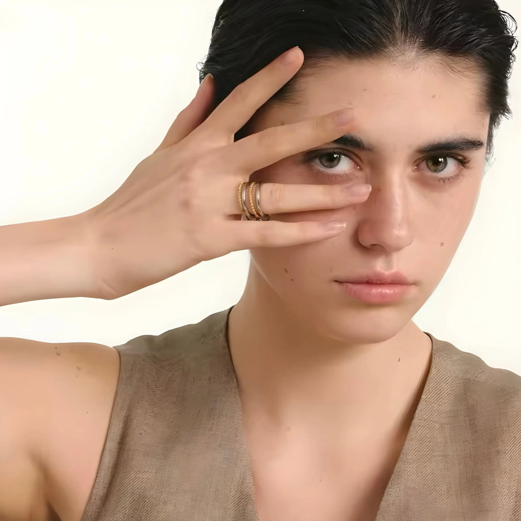 Onda BEHI MILANO zweifarbiger Ring aus 18 Karat Gold und Stahl an der Hand eines Modells mit braunem Oberteil und intensivem Look