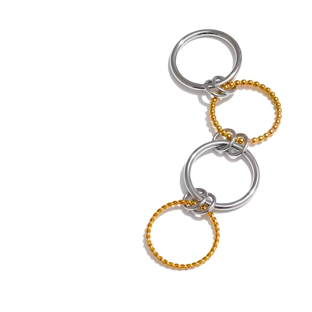 BEHI MILANO zweifarbiger Onda-Ring mit 2 glatten Stahlringen und 2 strukturierten 18-Karat-Goldringen auf weißem Hintergrund. Raffiniert.