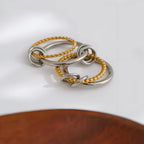 Onda BEHI MILANO Ring aus zweifarbigem 18-Karat-Gold und Stahl, fließendes Design mit ineinander verschlungenen Elementen und Kugeln auf weißem Hintergrund.