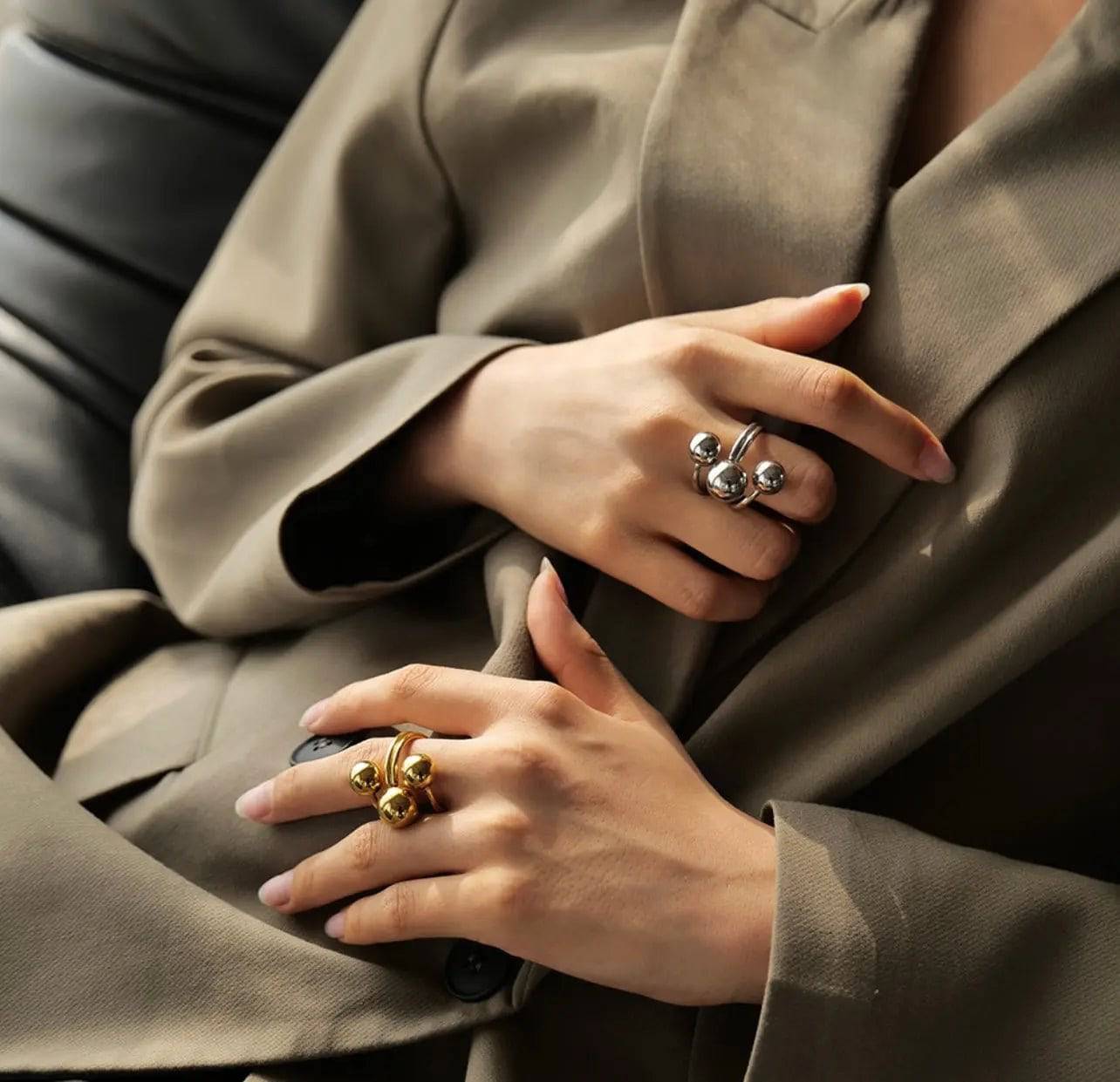 Anello BEHI MIA donna, uno placcato oro 18k con sfere e uno argento, indossati su mani eleganti con blazer.