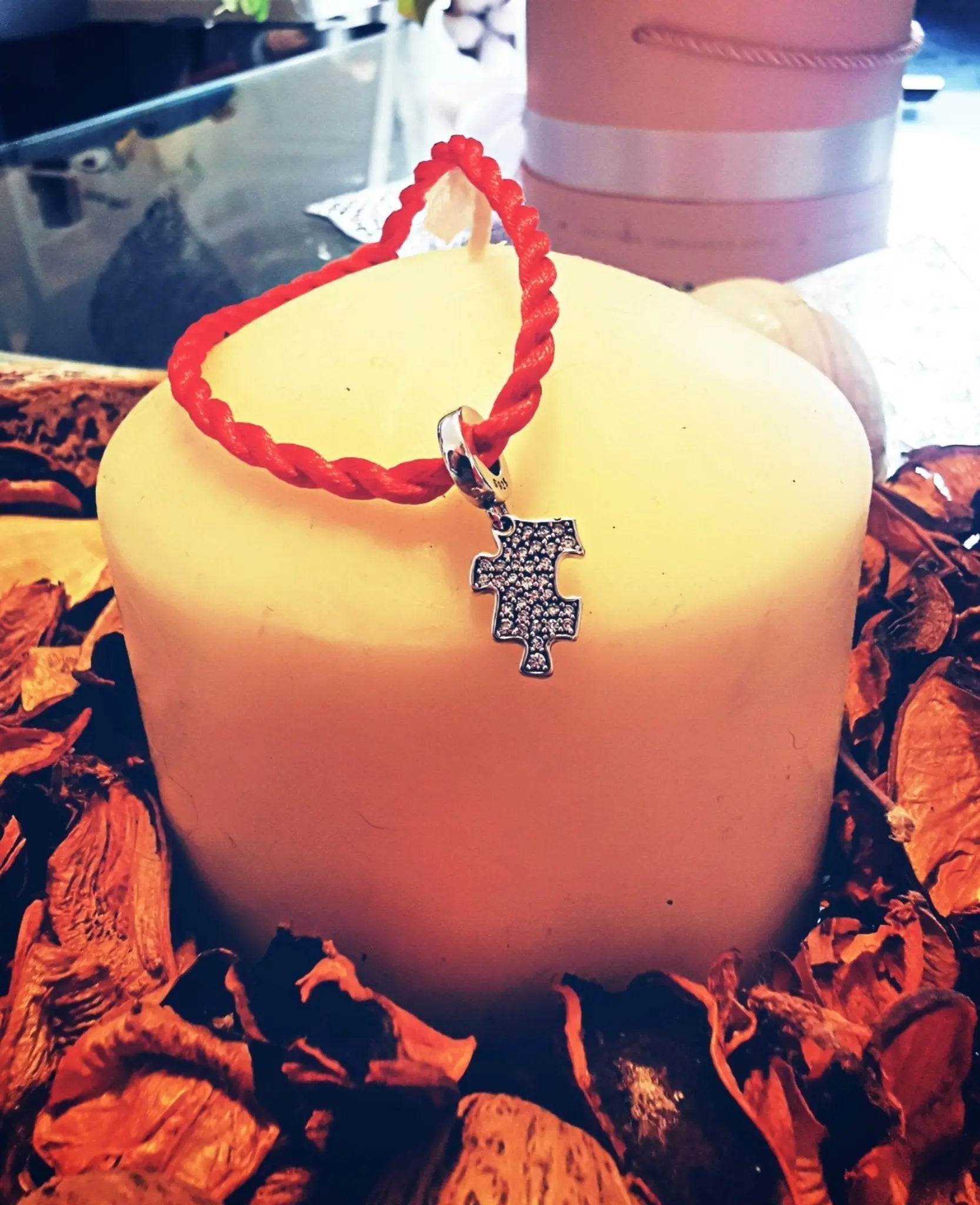 Charm puzzle argento S925 con zirconi, su candela chiara e petali. Ideale per bracciale Filo Rosso.