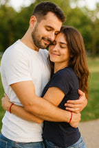 Giovane coppia si abbraccia, mostrando il Bracciale Filo Rosso del Destino ai polsi, stile raffinato