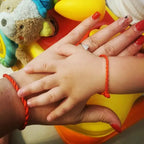 Mani di madre e figlio con bracciali Filo Rosso. Simbolo di legame, protezione e stile raffinato, gioielli artigianali.