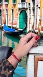 Bracciale Filo Rosso del Destino al polso, gondola sul canale di Venezia, palazzi sullo sfondo. Stile raffinato.