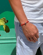 Bracciale Filo Rosso con charm argento S925 "Love is Forever" al polso, sfondo verde vivace, pianta di cactus