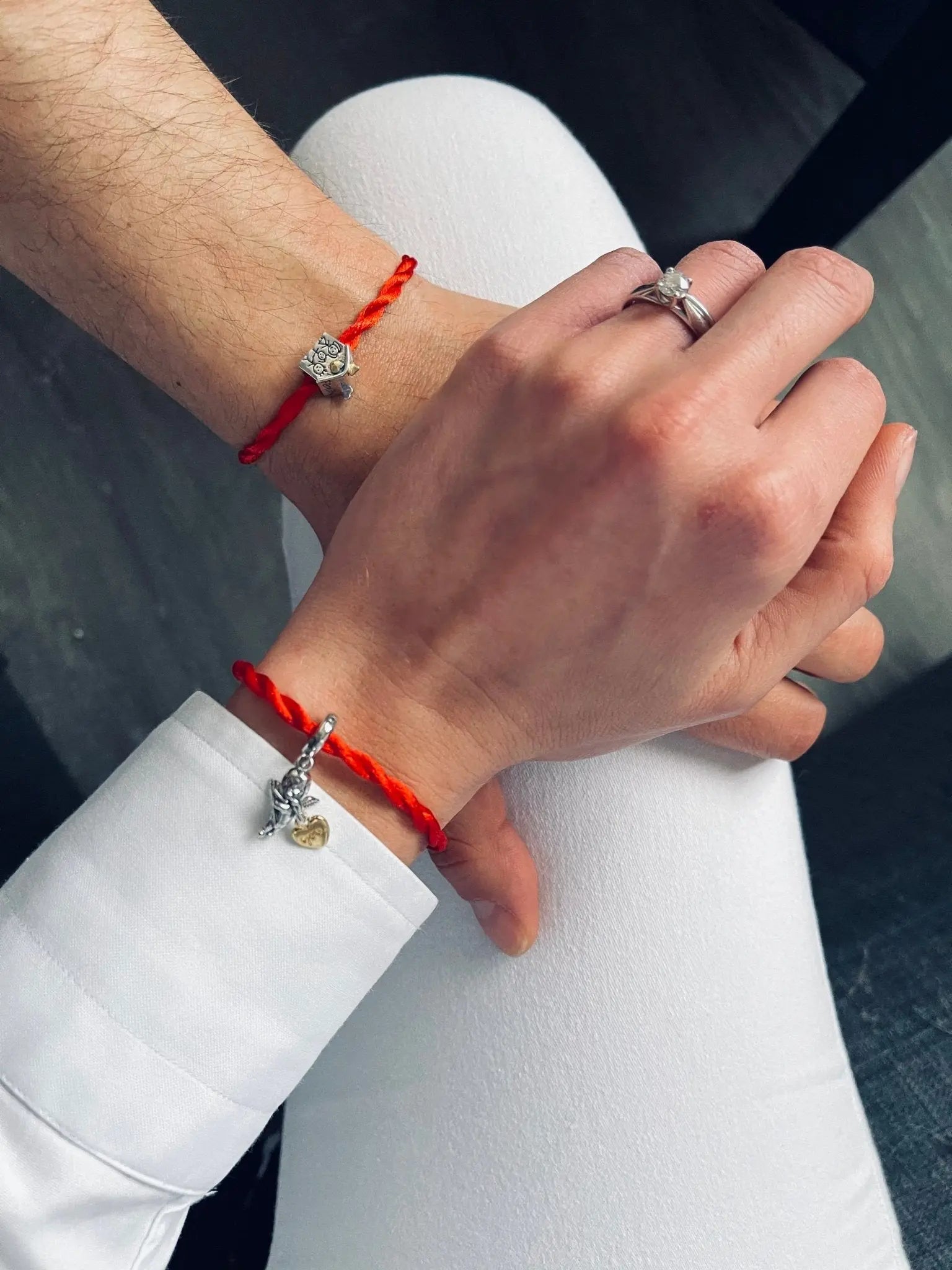 Coppia con bracciali Filo Rosso. Charm Cupido in Argento S925 al polso femminile e charm cuore al polso maschile.