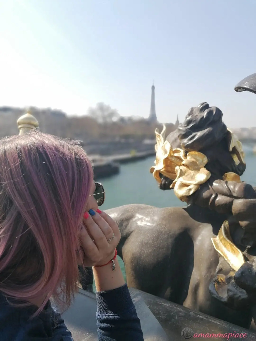 Donna con capelli rosa e bracciale Filo Rosso con Charm Cupido Argento S925, sullo sfondo la Torre Eiffel