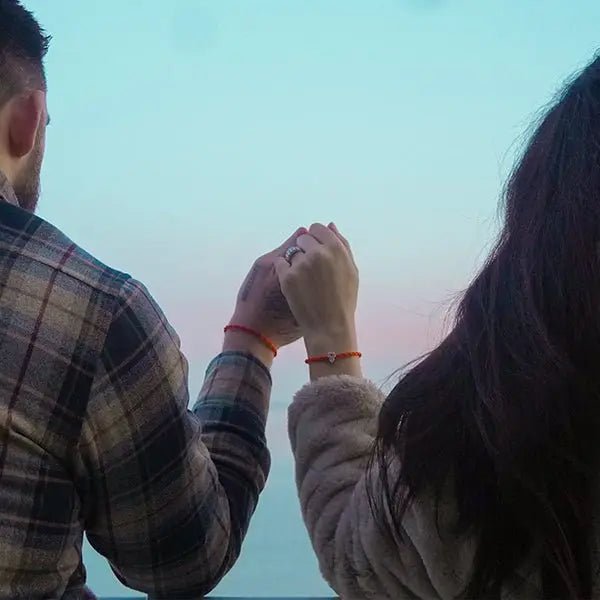 Mani unite con bracciali Filo Rosso, lei indossa charm Hamsa Argento S925, sfondo cielo al tramonto