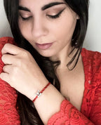 Donna con bracciale Filo Rosso del Destino e charm Renna Rudolph in Argento S925, primo piano su gilet rosso