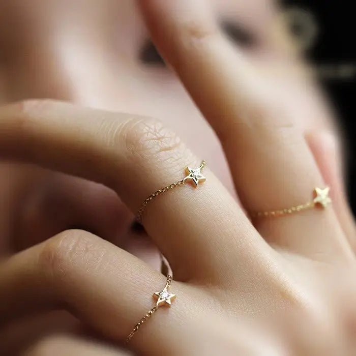 Anello regolabile a catena in oro 18K con stella e diamante, su dito di donna.
