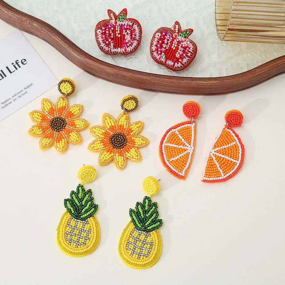 Orecchini pendenti artigianali con perline che raffigurano fiori gialli, ananas e mezza arancia. Gioielli di frutta.