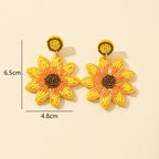 Orecchini pendenti artigianali a forma di girasole con perline gialle e arancioni, lunghi 6.5cm, larghi 4.8cm.