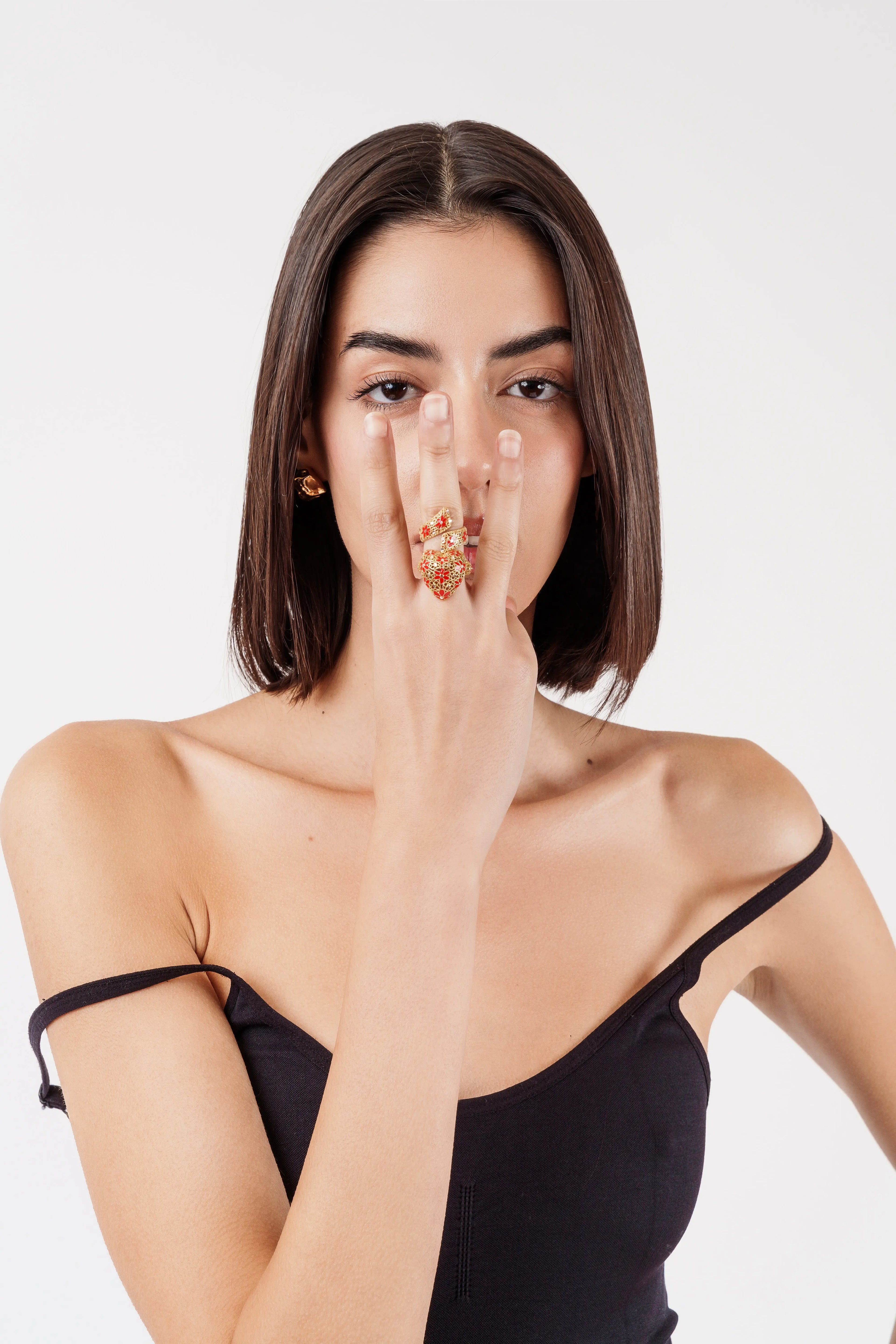 Donna con anello regolabile Drama Baby placcato oro 18k e smaltato rosso, con mano sul viso.