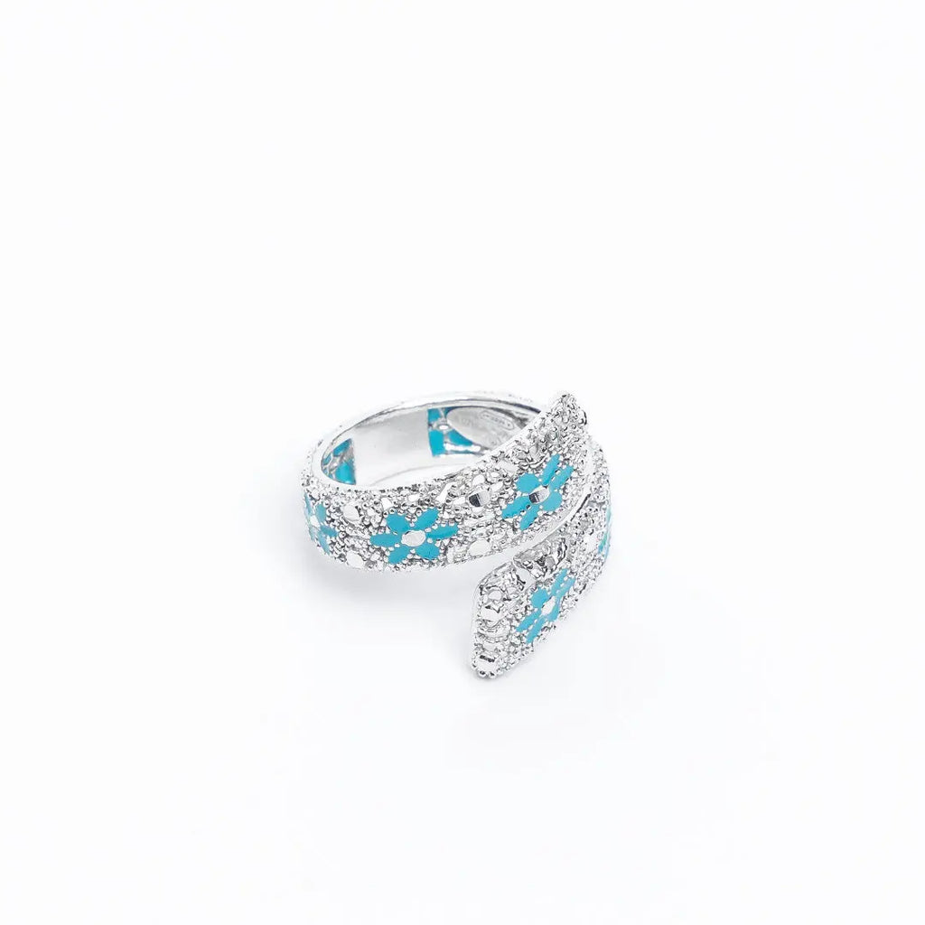 Verstellbarer Drama Baby-Ring aus 925er Silber, handemailliert in Türkis mit Blumenmotiv auf weißem Hintergrund.