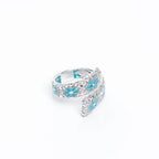 Verstellbarer Drama Baby-Ring aus 925er Silber, handemailliert in Türkis mit Blumenmotiv auf weißem Hintergrund.