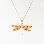 Collana WING IT in argento 925 placcato oro 18k con pendente a forma di libellula con strass rossi e bianchi su sfondo bianco