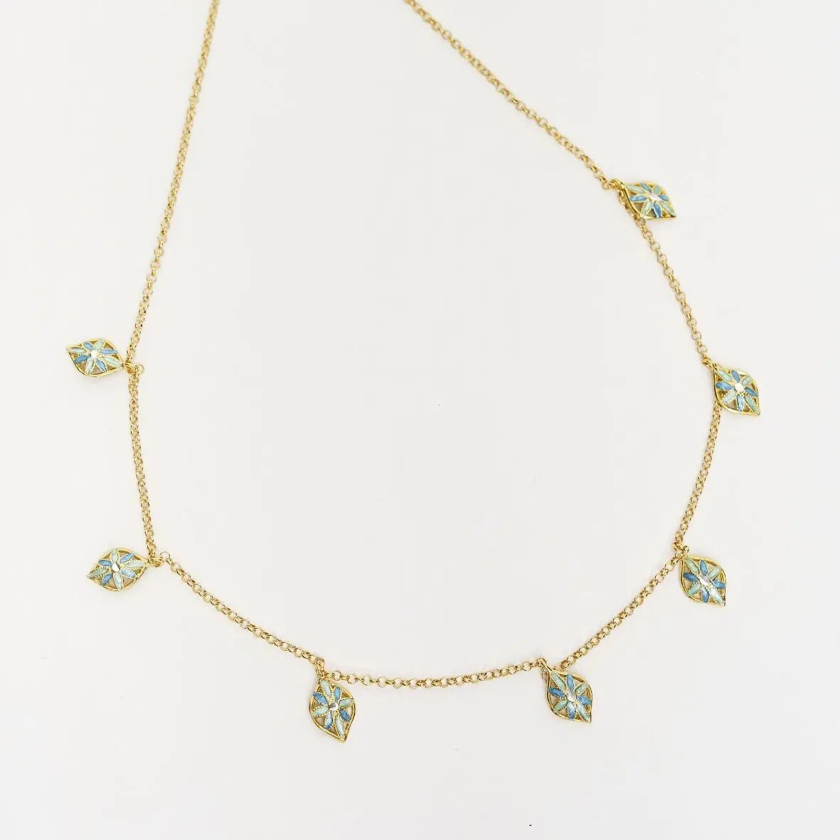 Collana multifoglie 'Leaf Me' in argento 925 placcato oro 18k con ciondoli smaltati azzurro e blu, su sfondo bianco.